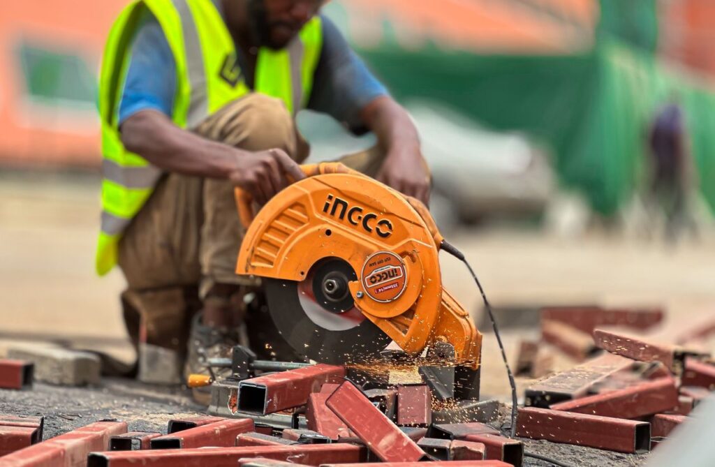 Worker using circular saw to cut metal on a construction site.